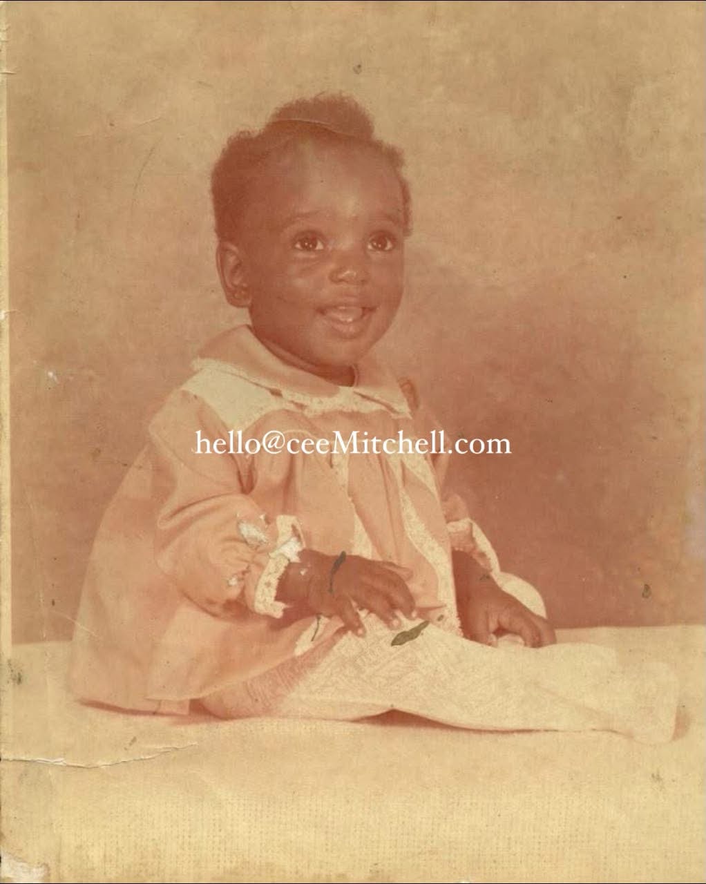 Cee Mitchell as a smiling baby, with the email address hello@ceeMitchell.com